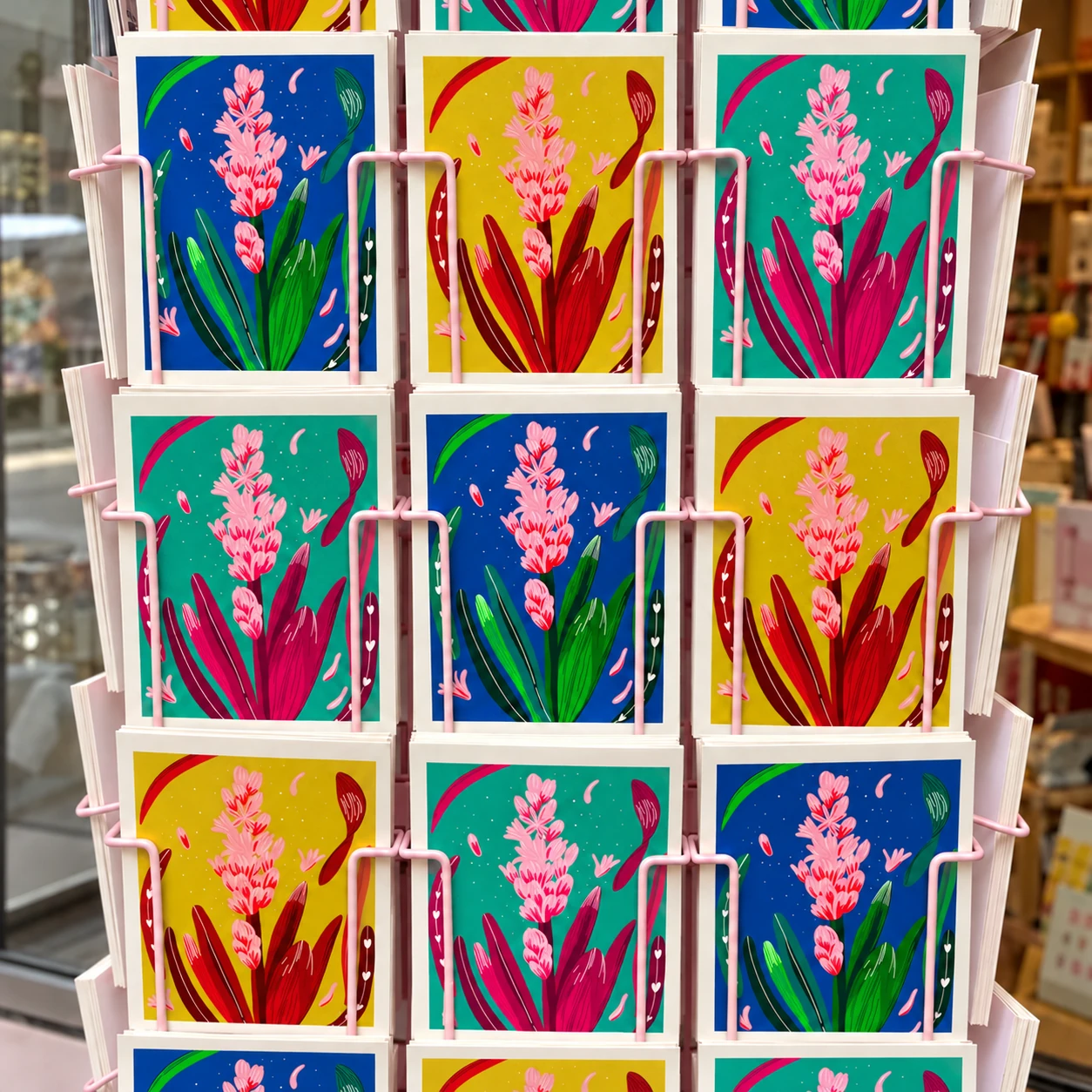 Les trois coloris des cartes Jacinthe présentés sur un présentoir rose